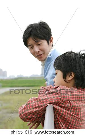 Stock Photograph - Side profile of a mid adult man talking to his son. Fotosearch