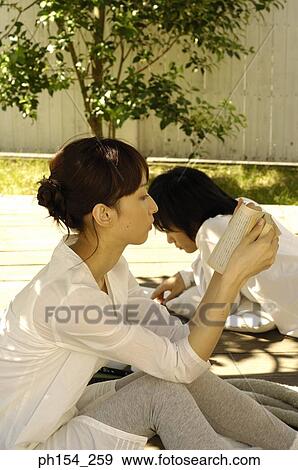 Stock Photo - Side profile of a young couple reading books. Fotosearch