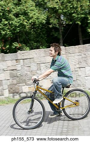 Stock Image - Side profile of a young man cycling. Fotosearch