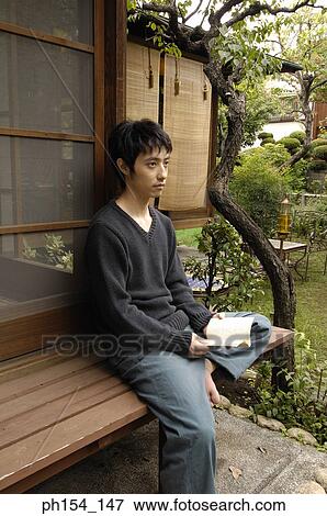 Side profile of a young man holding a book and thinking View Large Photo Image Stock Photo - Side profile of a young man holding a book and thinking. Fotosearch