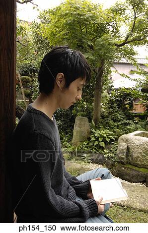 Stock Image - Side profile of a young man reading a book. Fotosearch
