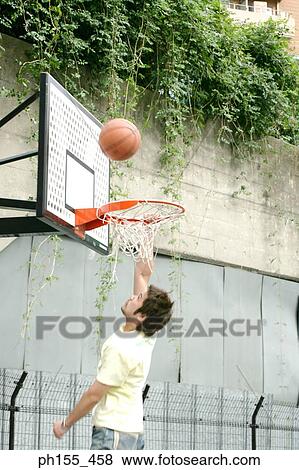Side profile of a young man shooting a basketball into a hoop View Large Photo Image Stock Photo - Side profile of a young man shooting a basketball into a hoop. Fotosearch