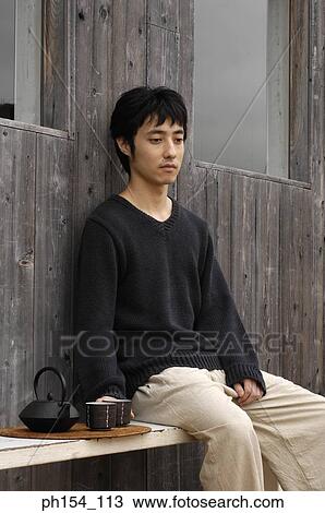 Side profile of a young man sitting on a bench View Large Photo Image Stock Image - Side profile of a young man sitting on a bench. Fotosearch