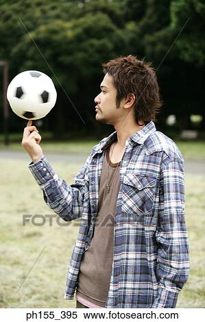 Stock Photography - Side profile of a young man spinning a soccer ball on his finger. Fotosearch