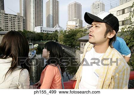 Stock Photo - Side profile of a young man standing with his three friends and looking away. Fotosearch