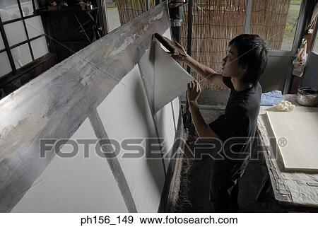 Stock Photo - Side profile of a young man sticking a sheet of paper on a board. Fotosearch