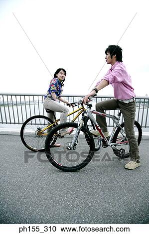 Side profile of a young woman and a young man sitting on bicycles View Large Photo Image Stock Image - Side profile of a young woman and a young man sitting on bicycles. Fotosearch