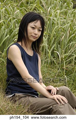 Side profile of a young woman sitting on the grass View Large Photo Image Picture - Side profile of a young woman sitting on the grass. Fotosearch