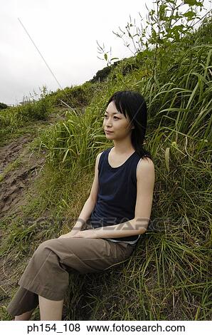 Stock Photo - Side profile of a young woman sitting on the grass. Fotosearch