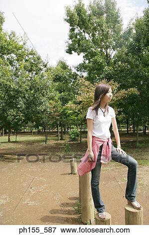 Side profile of a young woman standing on wooden posts View Large Photo Image Stock Photo - Side profile of a young woman standing on wooden posts. Fotosearch