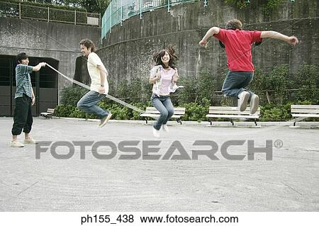 Three young men and a young woman playing jump rope View Large Photo Image Stock Photo - Three young men and a young woman playing jump rope. Fotosearch