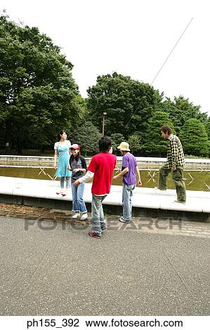 Three young men and two young women at a park View Large Photo Image Stock Image - Three young men and two young women at a park. Fotosearch