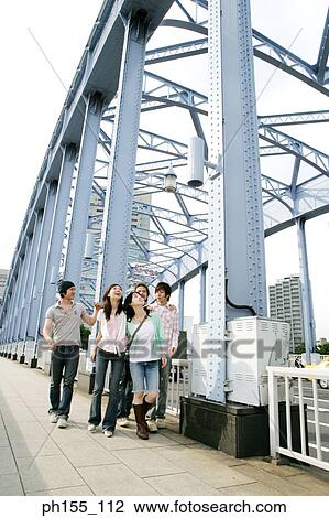 Stock Image - Three young men and two young women walking together. Fotosearch
