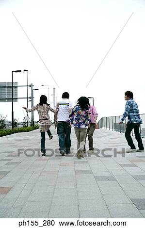 Three young men and two young women walking on the road View Large Photo Image Stock Image - Three young men and two young women walking on the road. Fotosearch
