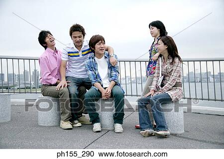 Stock Image - Three young men and two young women talking to each other. Fotosearch