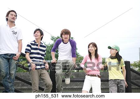 Three young men and two young women leaning on a railing and looking away View Large Photo Image Stock Image - Three young men and two young women leaning on a railing and looking away. Fotosearch