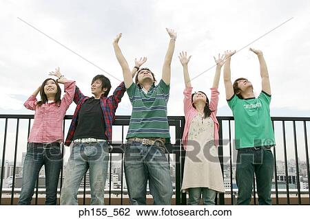 Three young men and two young women standing in front of a railing View Large Photo Image Stock Image - Three young men and two young women standing in front of a railing. Fotosearch