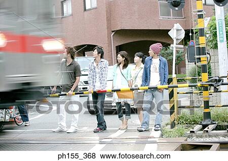 Three young men and two young women standing at a railroad crossing View Large Photo Image Stock Photo - Three young men and two young women standing at a railroad crossing. Fotosearch