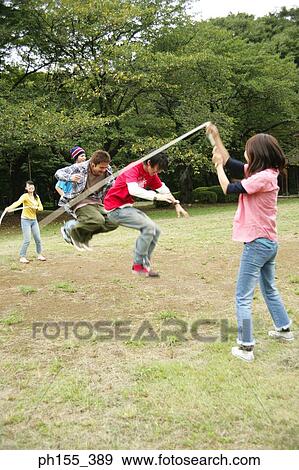 Three young men and two young women playing jump rope View Large Photo Image Stock Photo - Three young men and two young women playing jump rope. Fotosearch