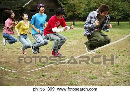 Three young men and two young women playing jump rope View Large Photo Image Stock Photo - Three young men and two young women playing jump rope. Fotosearch