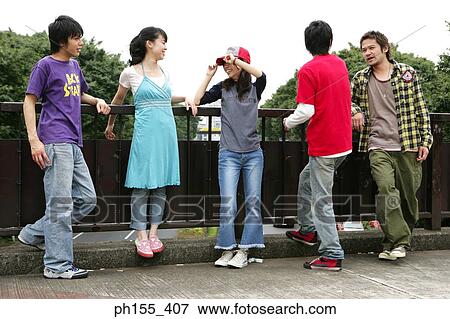 Three young men and two young women leaning against a railing View Large Photo Image Stock Photo - Three young men and two young women leaning against a railing. Fotosearch