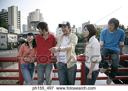 Three young men and two young women leaning on a railing and looking away View Large Photo Image Stock Photo - Three young men and two young women leaning on a railing and looking away. Fotosearch
