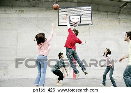 Stock Photograph - Three young men and two young women playing basketball. Fotosearch