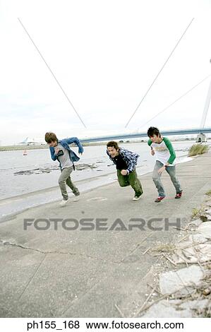 Three young men running near a river View Large Photo Image Stock Photo - Three young men running near a river. Fotosearch
