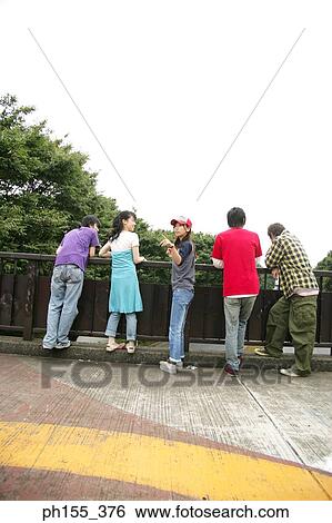 Three young women and two young men leaning against a railing View Large Photo Image Stock Photograph - Three young women and two young men leaning against a railing. Fotosearch