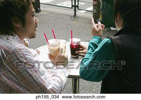 Two people sitting together and holding glasses in a restaurant View Large Photo Image Picture - Two people sitting together and holding glasses in a restaurant. Fotosearch