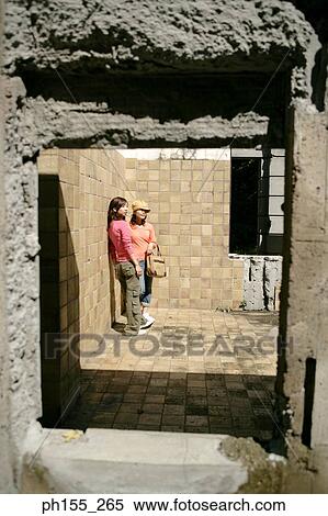 Two women standing beside a wall View Large Photo Image Stock Photography - Two women standing beside a wall. Fotosearch