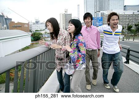 Two young men and two young women walking on a bridge View Large Photo Image Stock Image - Two young men and two young women walking on a bridge. Fotosearch