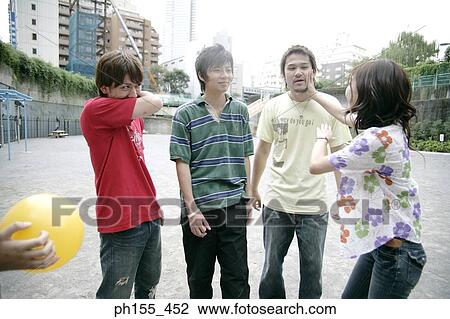 Stock Image - Two young men and two young women standing. Fotosearch