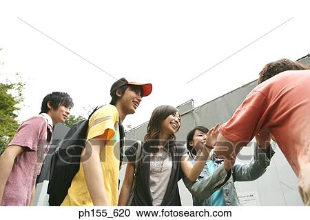 Two young men and two young women looking at a man View Large Photo Image Stock Image - Two young men and two young women looking at a man. Fotosearch