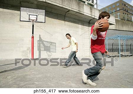 Two young men playing basketball View Large Photo Image Stock Photo - Two young men playing basketball. Fotosearch