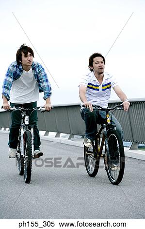 Two young men riding bicycles View Large Photo Image Stock Photography - Two young men riding bicycles. Fotosearch