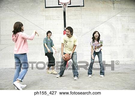 Two young men with two young women playing basketball View Large Photo Image Stock Photo - Two young men with two young women playing basketball. Fotosearch