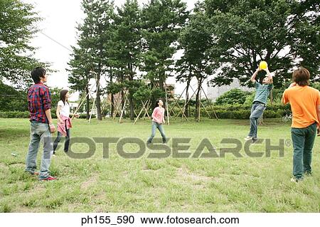 Stock Image - Two young women and three young men playing in the park. Fotosearch