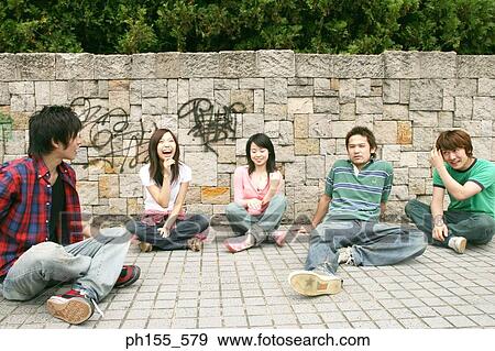 Stock Photo - Two young women and three young men sitting together. Fotosearch