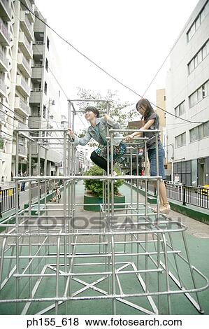Stock Photo - Two young women climbing a jungle gym. Fotosearch