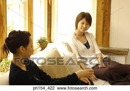 Two young women sitting on a couch View Large Photo Image Stock Image - Two young women sitting on a couch. Fotosearch
