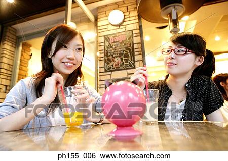 Two young women sitting together View Large Photo Image Stock Photograph - Two young women sitting together. Fotosearch