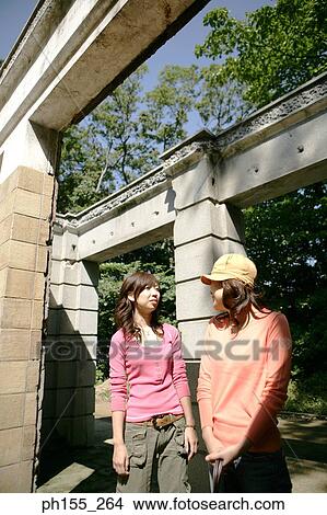 Two young women standing in front of a building View Large Photo Image Picture - Two young women standing in front of a building. Fotosearch