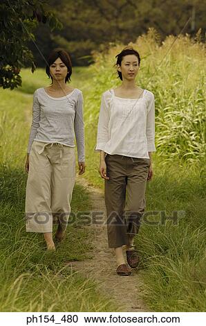 Two young women walking on a trail View Large Photo Image Stock Image - Two young women walking on a trail. Fotosearch