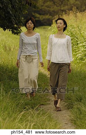 Two young women walking on a trail View Large Photo Image Stock Image - Two young women walking on a trail. Fotosearch