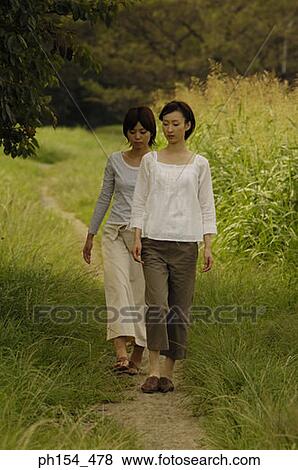 Two young women walking on a trail View Large Photo Image Stock Photo - Two young women walking on a trail. Fotosearch
