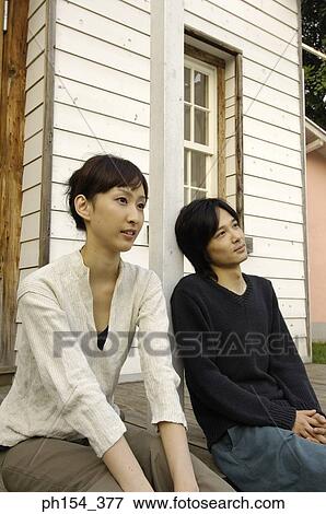 Stock Photo - Young couple sitting in front of a house. Fotosearch