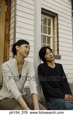 Stock Photograph - Young couple sitting in front of a house. Fotosearch