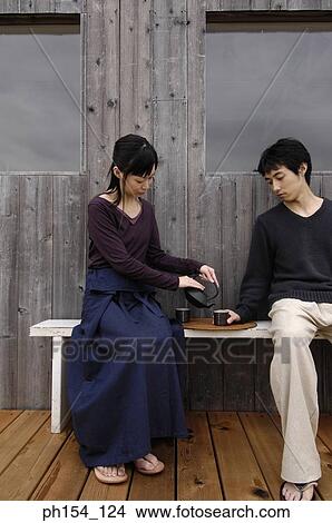 Young couple sitting on a bench and having tea View Large Photo Image Picture - Young couple sitting on a bench and having tea. Fotosearch