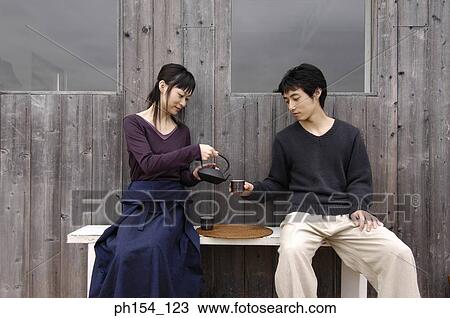 Young couple sitting on a bench and having tea View Large Photo Image Stock Image - Young couple sitting on a bench and having tea. Fotosearch